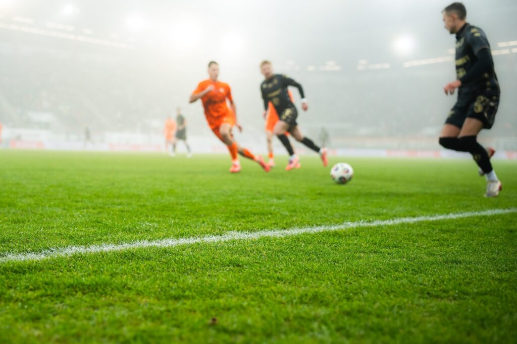 grass and sideline on the football pitch at the stadium and player's legs at the background